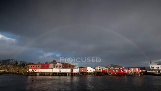 Arco iris sobre pueblo costero, Lofoten, Nordland, Noruega - foto de stock