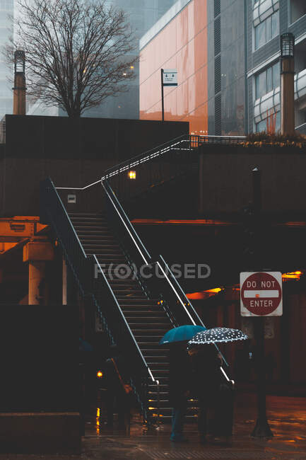 Two people walking up stairs carrying umbrellas, Chicago, Illinois, United States — Stock Photo