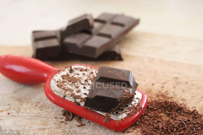Chocolate, rallador y chocolate rallado en una tabla de cortar - foto de stock