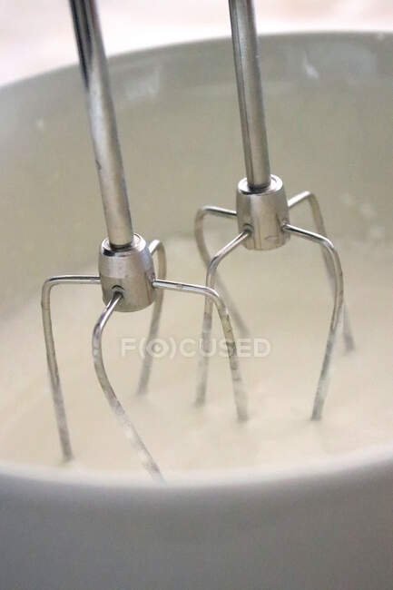 Close-up of an electric whisk and a bowl of double cream — Stock Photo