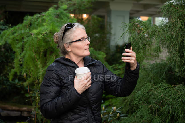 Femme debout à l'extérieur regardant son téléphone portable, Colombie-Britannique, Canada — Photo de stock