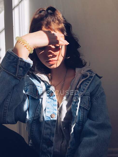 Porträt eines Teenagers, der sein Gesicht mit der Hand im Sonnenlicht verdeckt — Stockfoto