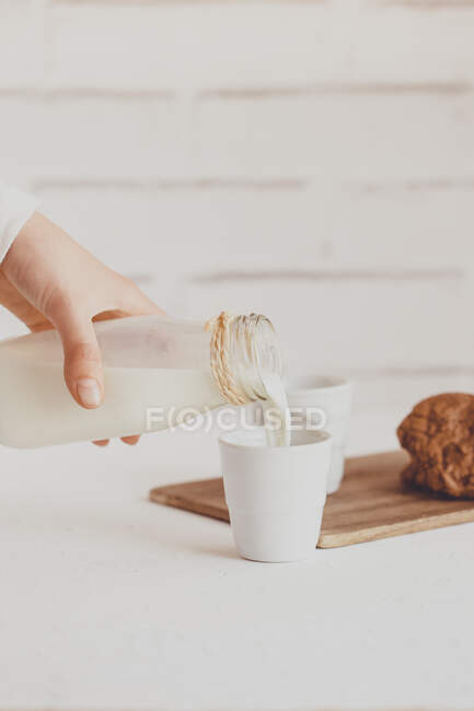 Enfant versant un verre de lait et une pile de biscuits au chocolat — Photo de stock