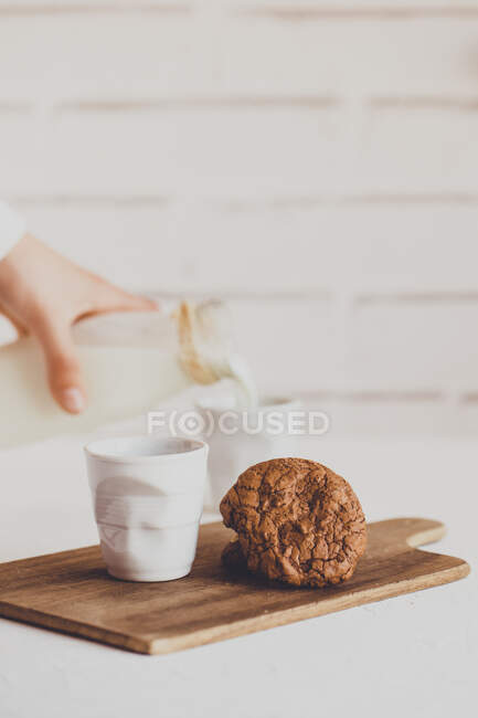 Criança derramando um copo de leite e uma pilha de biscoitos de chocolate — Fotografia de Stock