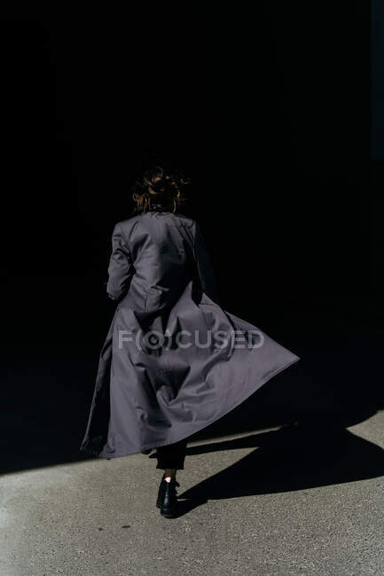 Rückansicht einer Frau, die im Trenchcoat davonläuft — Stockfoto