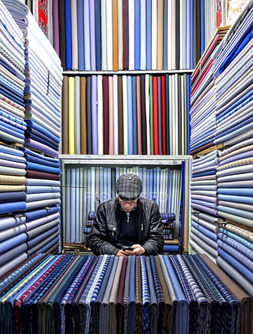 Textilverkäufer checkt sein Handy, Iran — Stockfoto