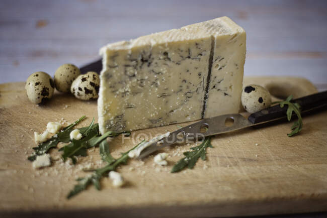 Gorgonzola cheese on a chopping board with quail eggs — Stock Photo