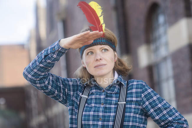 Woman dressed up in North American tribal costume shielding her eyes, Germany — Stock Photo