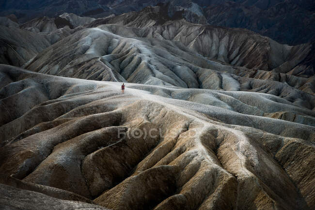 Woman walking along the rim of the Badlands, Death Valley, California, United States — Stock Photo