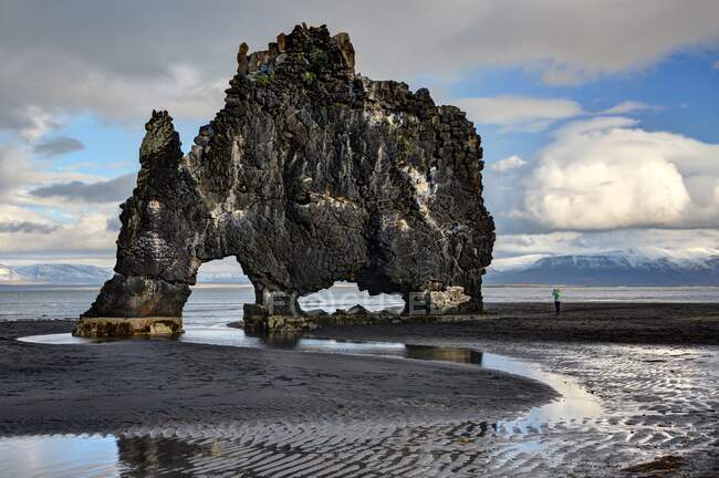 Hombre de pie junto a Hvitserkur, Península de Vatnsnes, Islandia - foto de stock