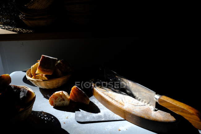Breadboard, faca e pão em uma mesa à luz do sol — Fotografia de Stock