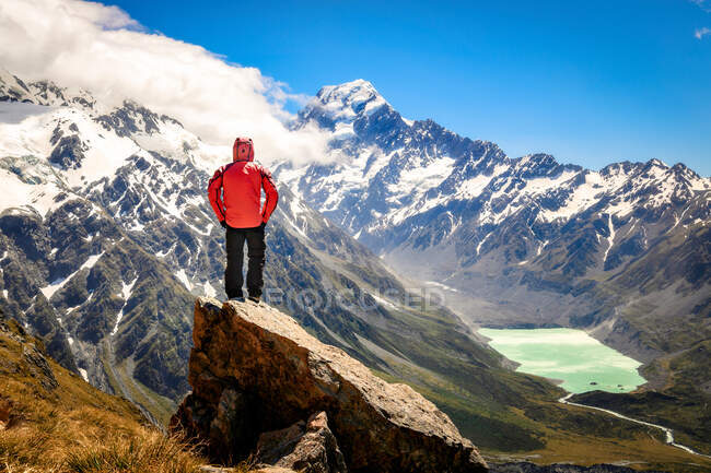 Vue arrière de l'homme debout sur le rocher en face des montagnes — Photo de stock