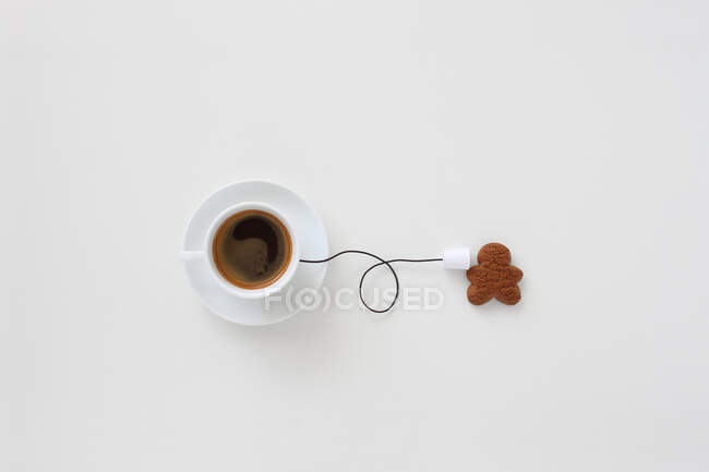 Conceptual cup of coffee string phone and a gingerbread man — Stock Photo