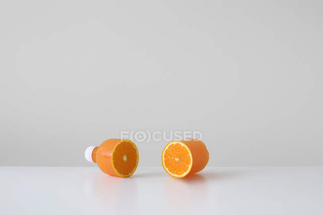 Концептуальна пляшка апельсинового соку, розрізана навпіл з справжнім апельсином всередині — стокове фото