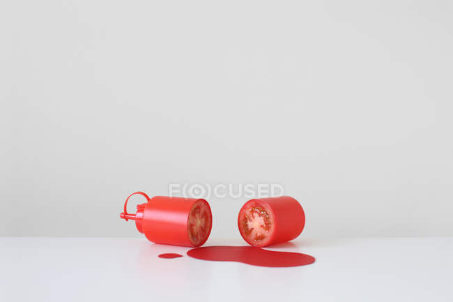 Концептуальна пляшка кетчупу, розрізана навпіл з справжнім помідором всередині — стокове фото