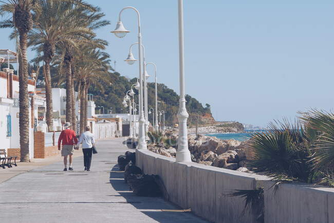 Couple de personnes âgées marchant le long d'une promenade sur la plage, Malaga, Espagne — Photo de stock
