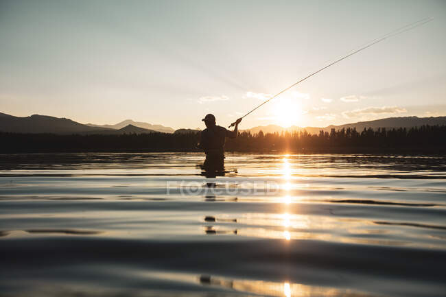 Silhouette of a man standing in a river fly fishing, United States — Stock Photo