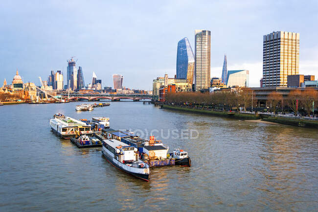 Paisaje urbano y barcos en el río Támesis al atardecer, Londres, Inglaterra, Reino Unido - foto de stock