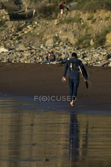 Surfista che trasporta una tavola da surf sulla spiaggia Sopelana, Vizcaya, Paesi Baschi, Spagna — Foto stock