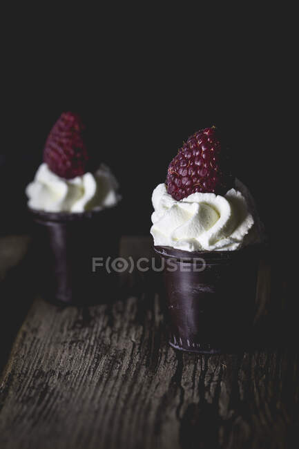 Pots de chocolat noir remplis de crème fouettée et de framboise — Photo de stock
