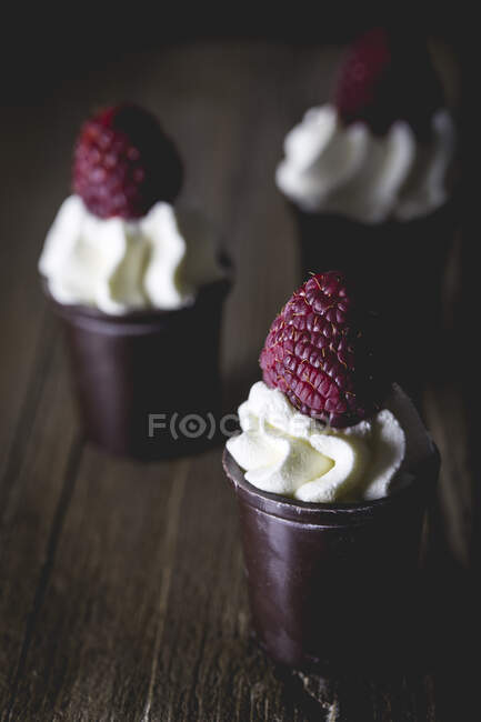 Dark chocolate pots filled with whipped cream and raspberry — Stock Photo