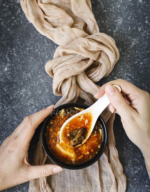 Mujer comiendo un tazón de sopa agria y caliente - foto de stock