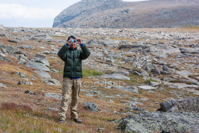 Мужчина, стоящий в горах и фотографирующий, США — стоковое фото