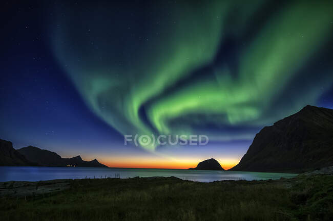 Green aurora borealis light over mountainous landscape with lake — Stock Photo