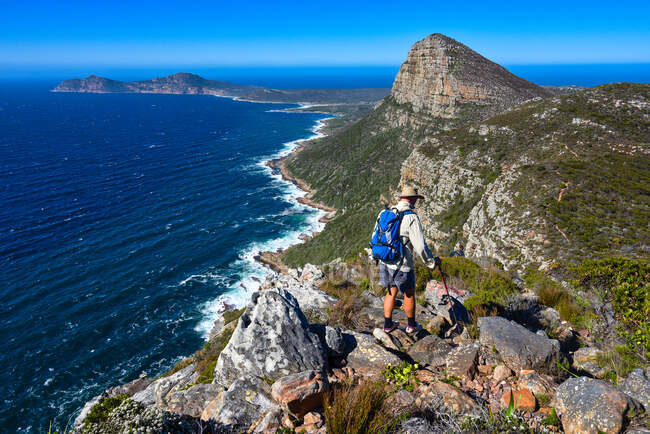 Randonneur debout sur le sentier de randonnée du Cap de Bonne-Espérance prenant une photo, Cap Ouest, Afrique du Sud — Photo de stock
