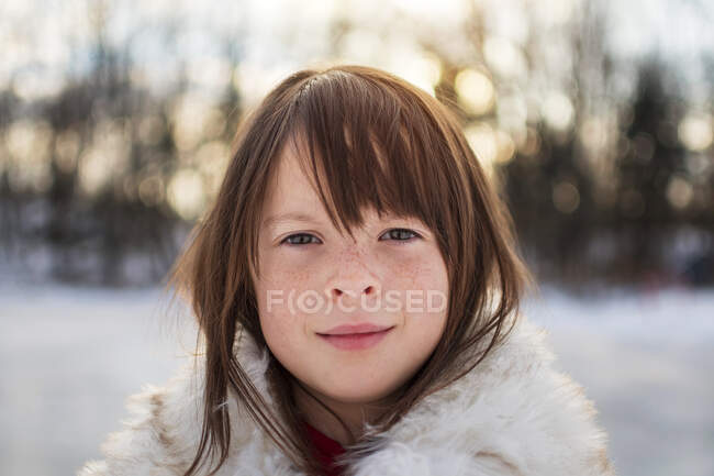 Retrato de una chica sonriente de pie en la nieve, Estados Unidos - foto de stock