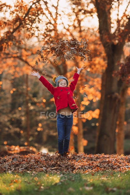 Menina jogando folhas de outono no ar, Estados Unidos — Fotografia de Stock