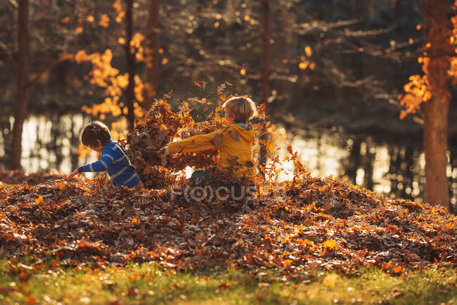 Zwei Jungen spielen in einem Laubhaufen, Vereinigte Staaten — Stockfoto