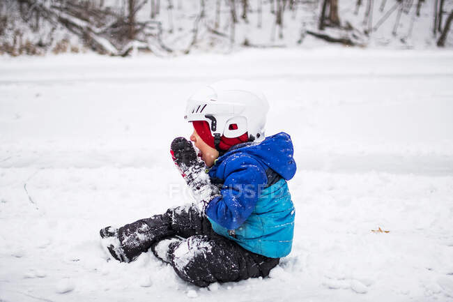 Boy sitting on frozen lake eating snow, Wisconsin, Stati Uniti — Foto stock