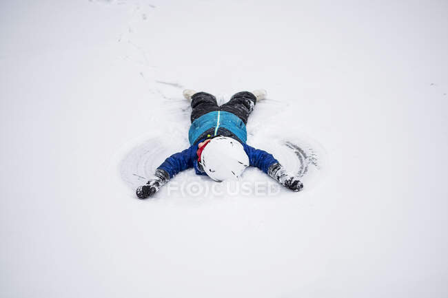 Junge liegt im Schnee und macht einen Schneengel, Wisconsin, Vereinigte Staaten — Stockfoto