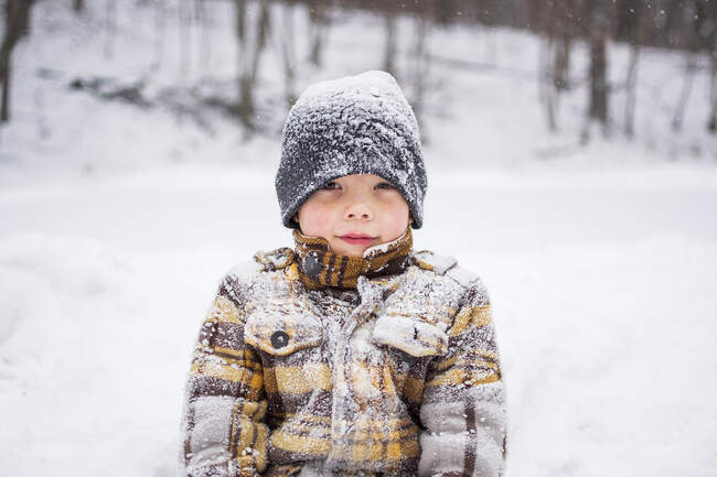 Portrait of boy child covered in snow in winter park scene — Stock Photo