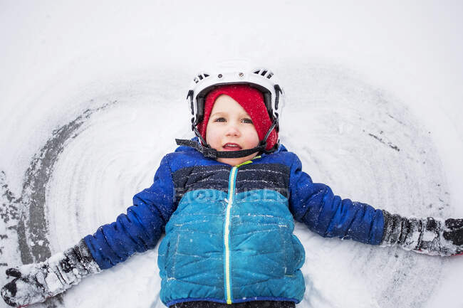 Junge liegt auf gefrorenem See und macht einen Schnee-Engel, Wisconsin, Vereinigte Staaten — Stockfoto