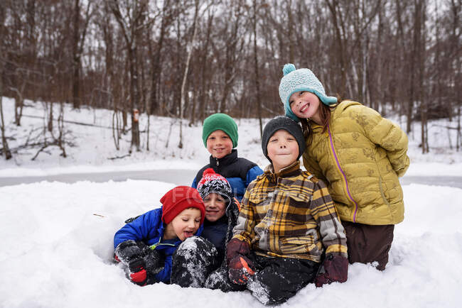П'ять щасливих дітей на снігу в зимовому лісі сцена — стокове фото