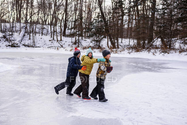 Tres niños caminando en un lago congelado, Wisconsin, Estados Unidos - foto de stock