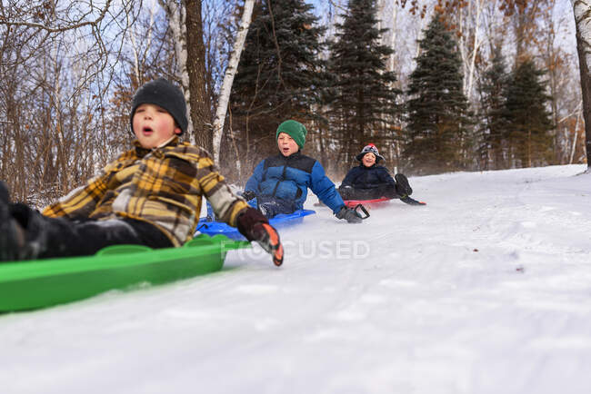Tres chicos en un trineo riendo, Wisconsin, Estados Unidos - foto de stock