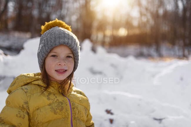 Portrait of a smiling girl standing next to a snow fort, United States — Stock Photo