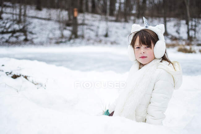 Ritratto di una ragazza con un paraorecchie da unicorno in piedi in un forte di neve, Stati Uniti — Foto stock