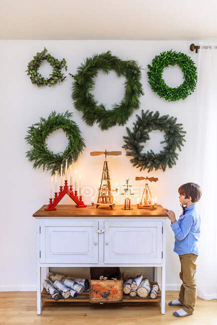 Мальчик стоит у буфета и смотрит на рождественские украшения — стоковое фото
