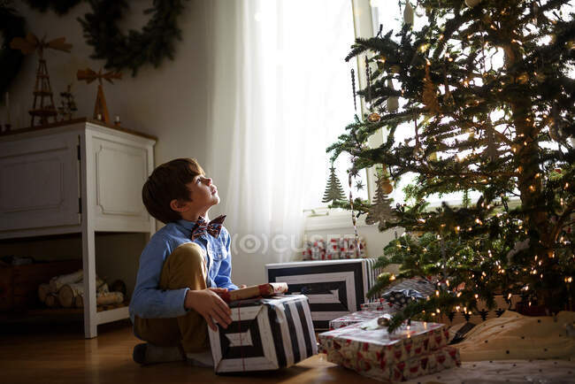 Junge kniet vor Weihnachtsbaum mit Geschenken — Stockfoto