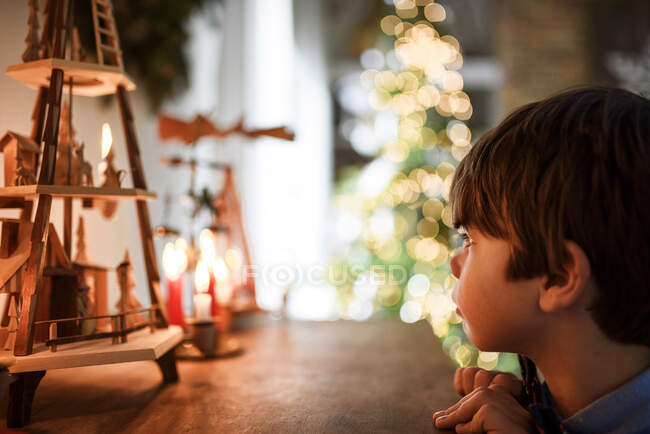 Junge schaut sich Weihnachtsschmuck und Kerzen an — Stockfoto
