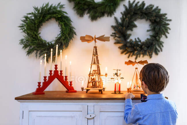 Junge steht vor einer Anrichte und betrachtet Weihnachtsdekoration — Stockfoto