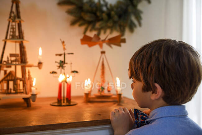 Ragazzo in piedi davanti a una credenza guardando le decorazioni natalizie — Foto stock
