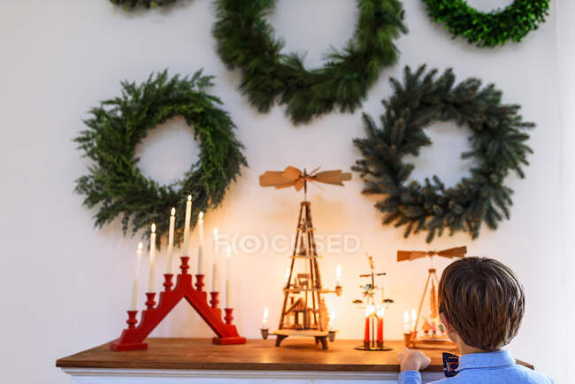 Niño de pie frente a un aparador mirando las decoraciones de Navidad - foto de stock