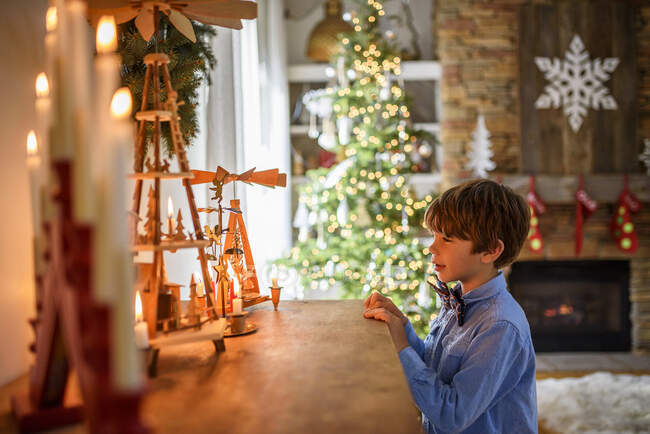 Garçon debout devant un buffet regardant les décorations de Noël — Photo de stock
