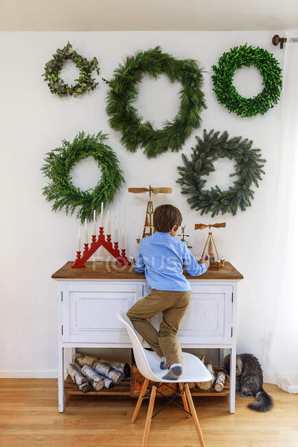 Boy standing on a chair in front of a sideboard — Stock Photo