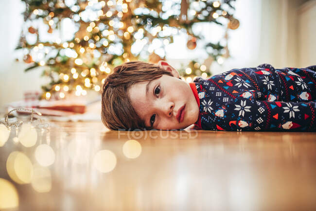 Хлопець лежав на підлозі перед ялинкою. — стокове фото